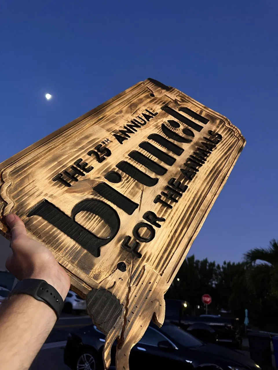CNC routed burnt wood event sign photographed at dusk