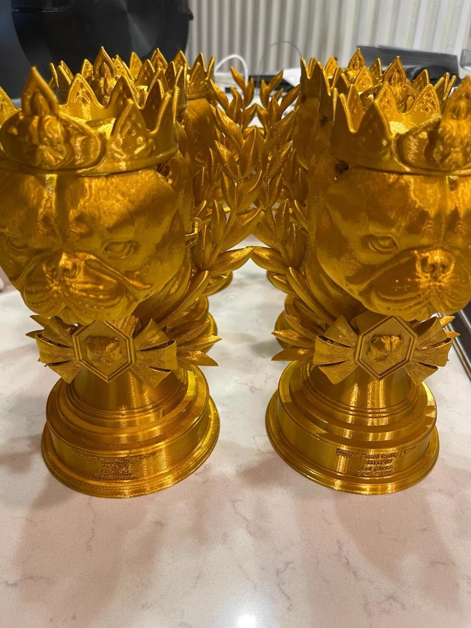 Batch of gold bulldog head crown trophies with laurel wreaths