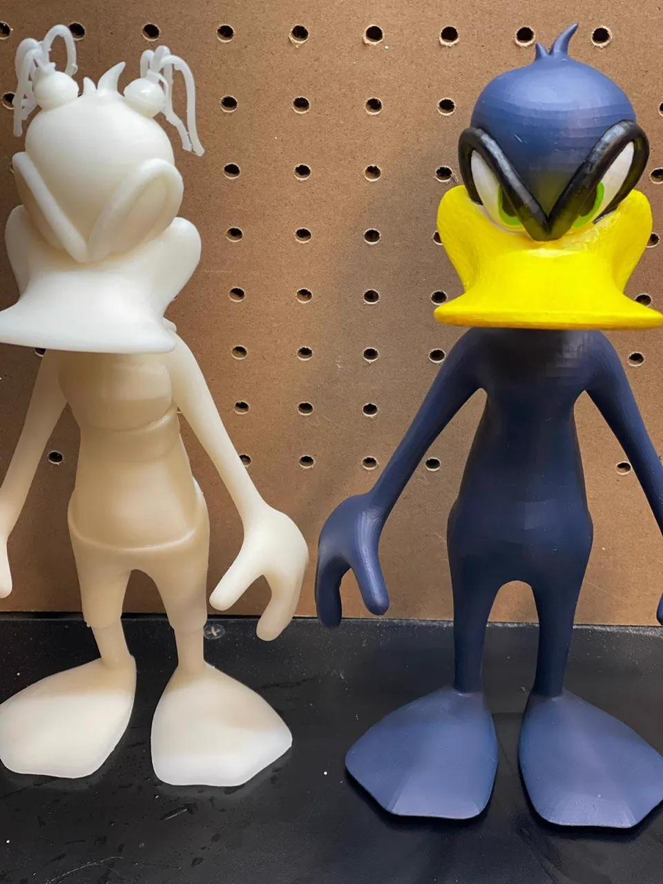 Raw white 3D print beside the same figure hand-painted in blue and yellow